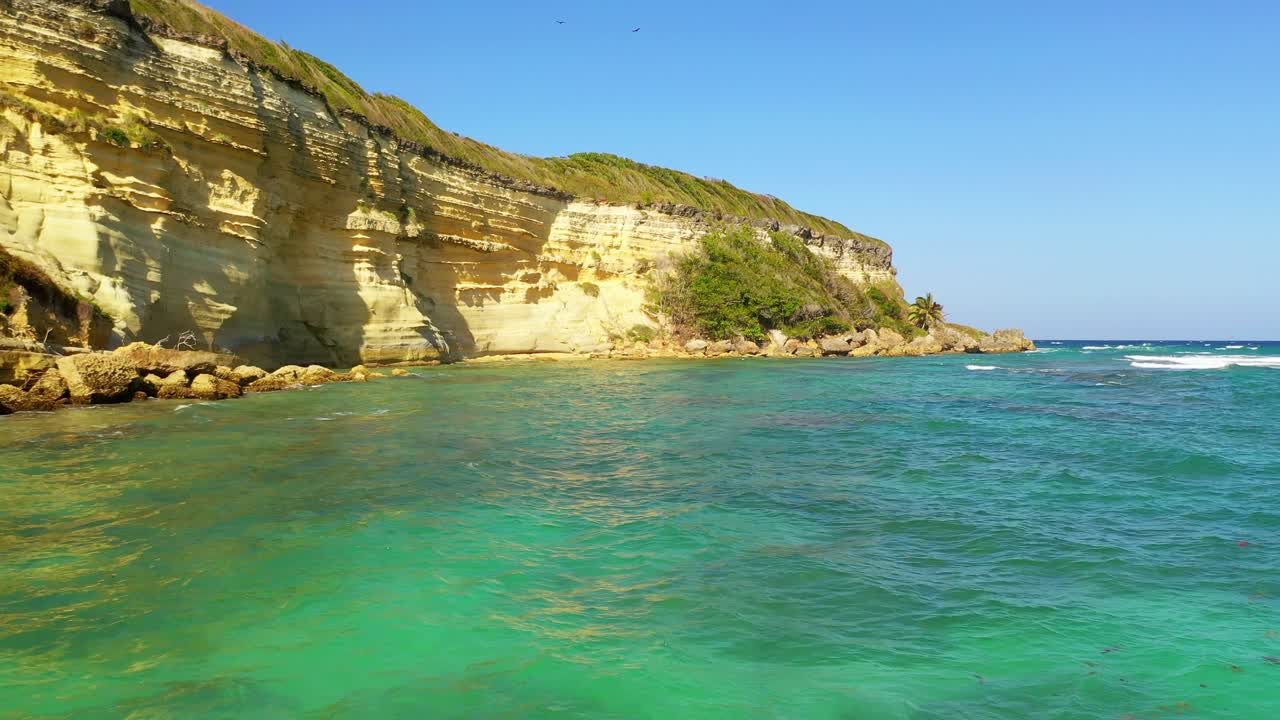 카브레라 도미니카 공화국의 카보 프란체스 비에조(cabo frances viejo) 배경에 있는 청록색 바다의 파도와 가파른 석회암 절벽 산을 향해 바위가 많은 모래 해변 위로 멋진 저공 비행