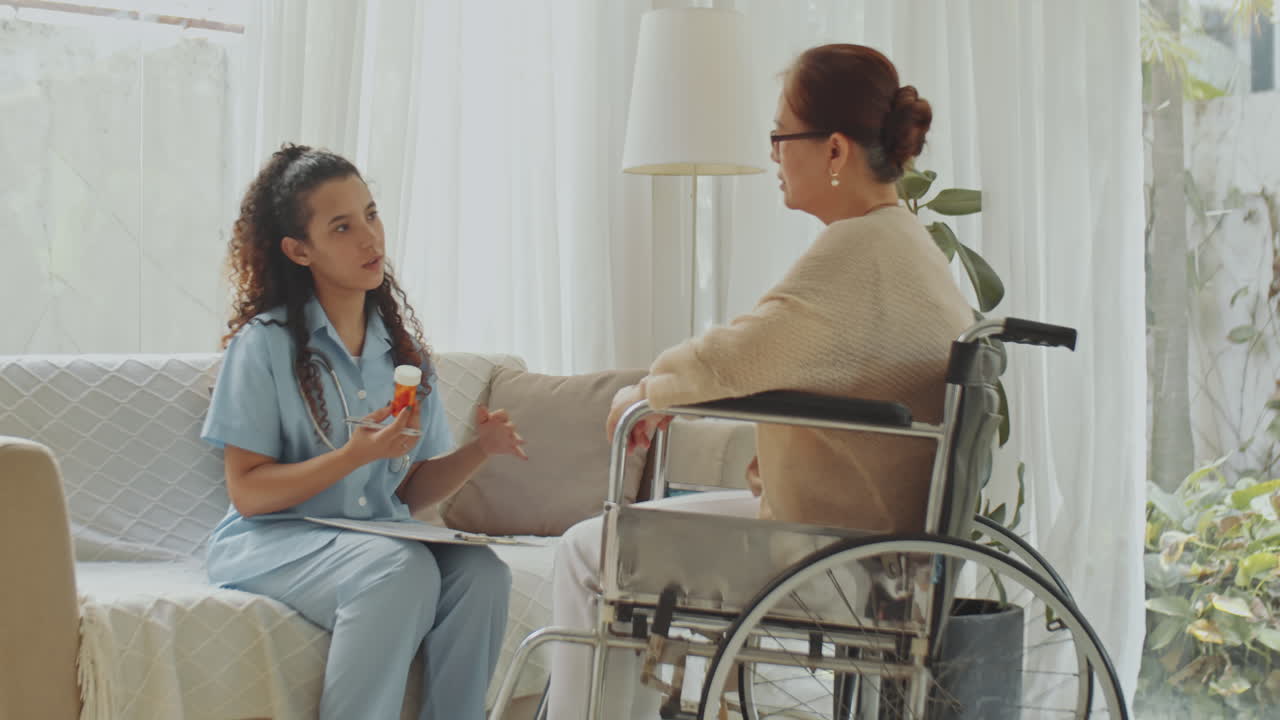 A caregiver consults with an elderly woman in a wheelchair
