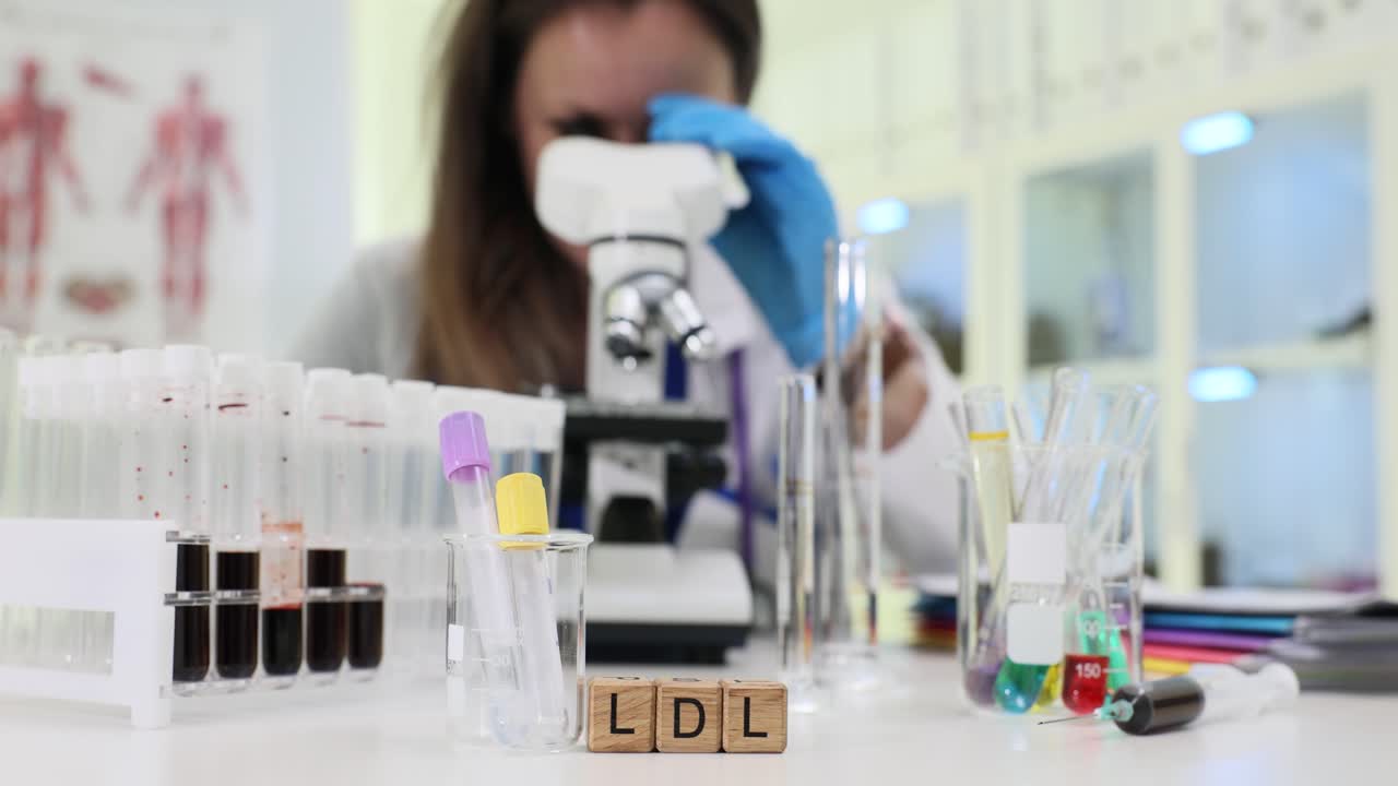 Woman laboratory worker examines ldl under microscope