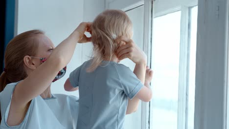 mother styling daughter's hair by the window