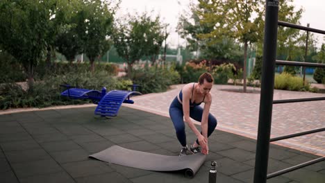 woman rolling up yoga mat outdoors