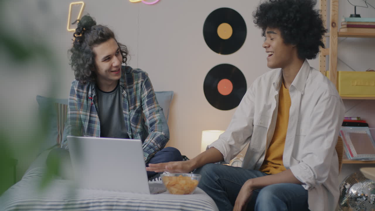 Teenagers Watching Something on a Laptop in a Bedroom