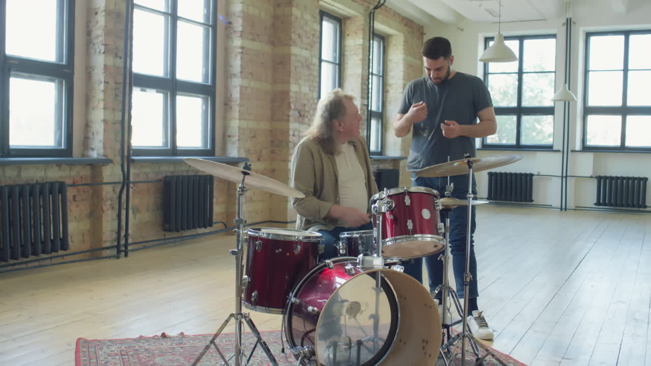 Senior Man Learning How to Play Drums with Young Teacher