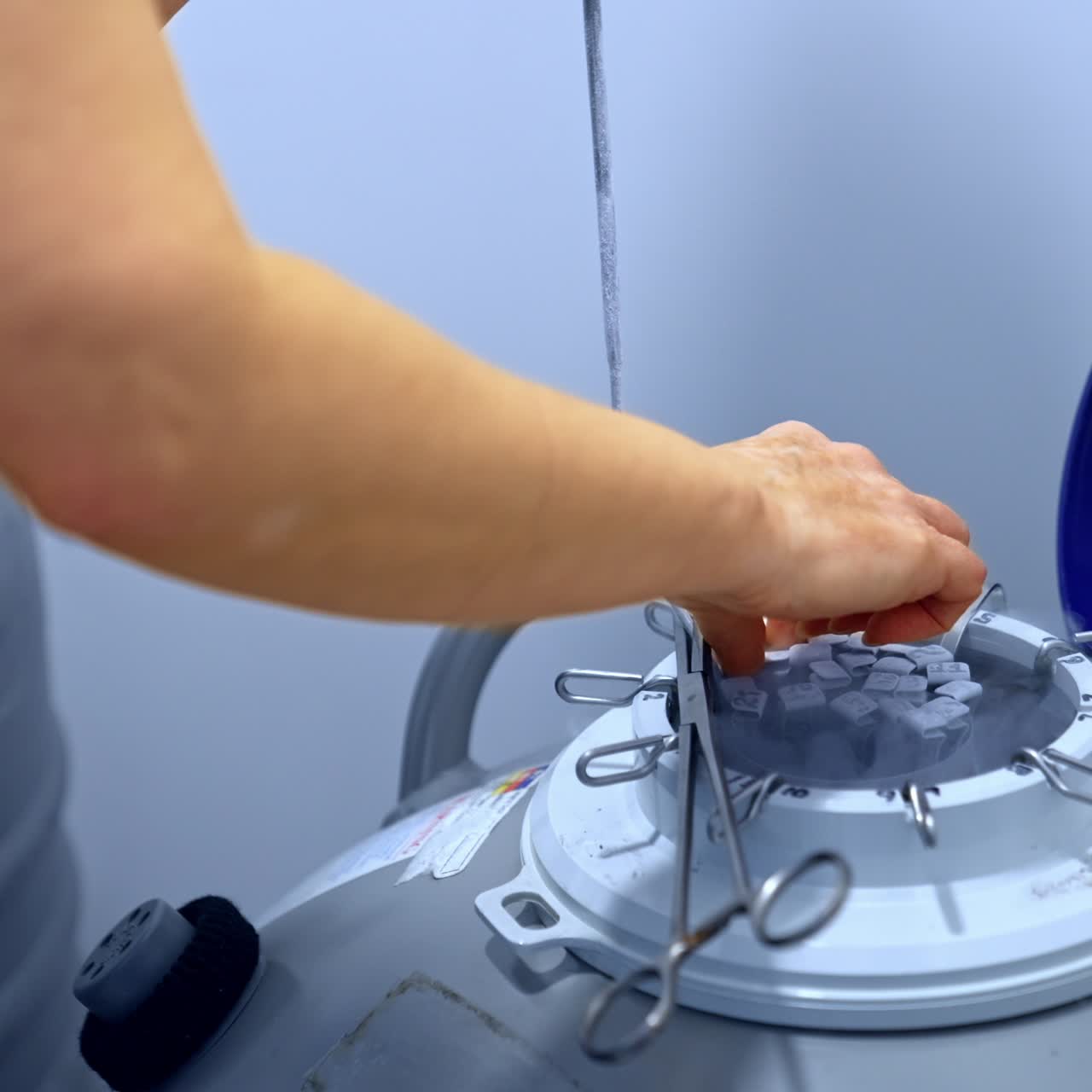 Medic opening the reservoir with frozen samples for IVF procedure. Specialist extracts the test tube from a tank