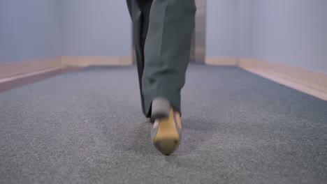 back view of businesswoman walking confidently in office, wearing stylish gray shoes on office carpet floor, showcasing professional attitude and fashion
