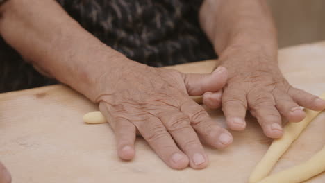 slow motion footage of old hands rolling pasta dough in italy