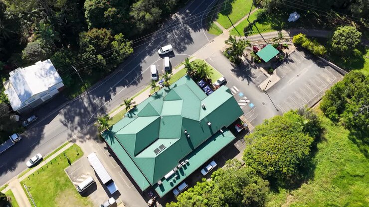 Aerial footage of a building surrounded by greenery in Uki, NSW, Australia. Bright daylight illuminates the scene