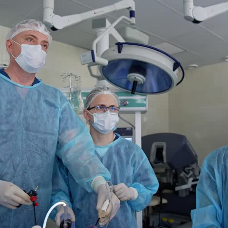 surgery specialists running operation in the modern surgery room. doctors using medical equipment, looking at the monitor and discussing the process. team of professionals at work