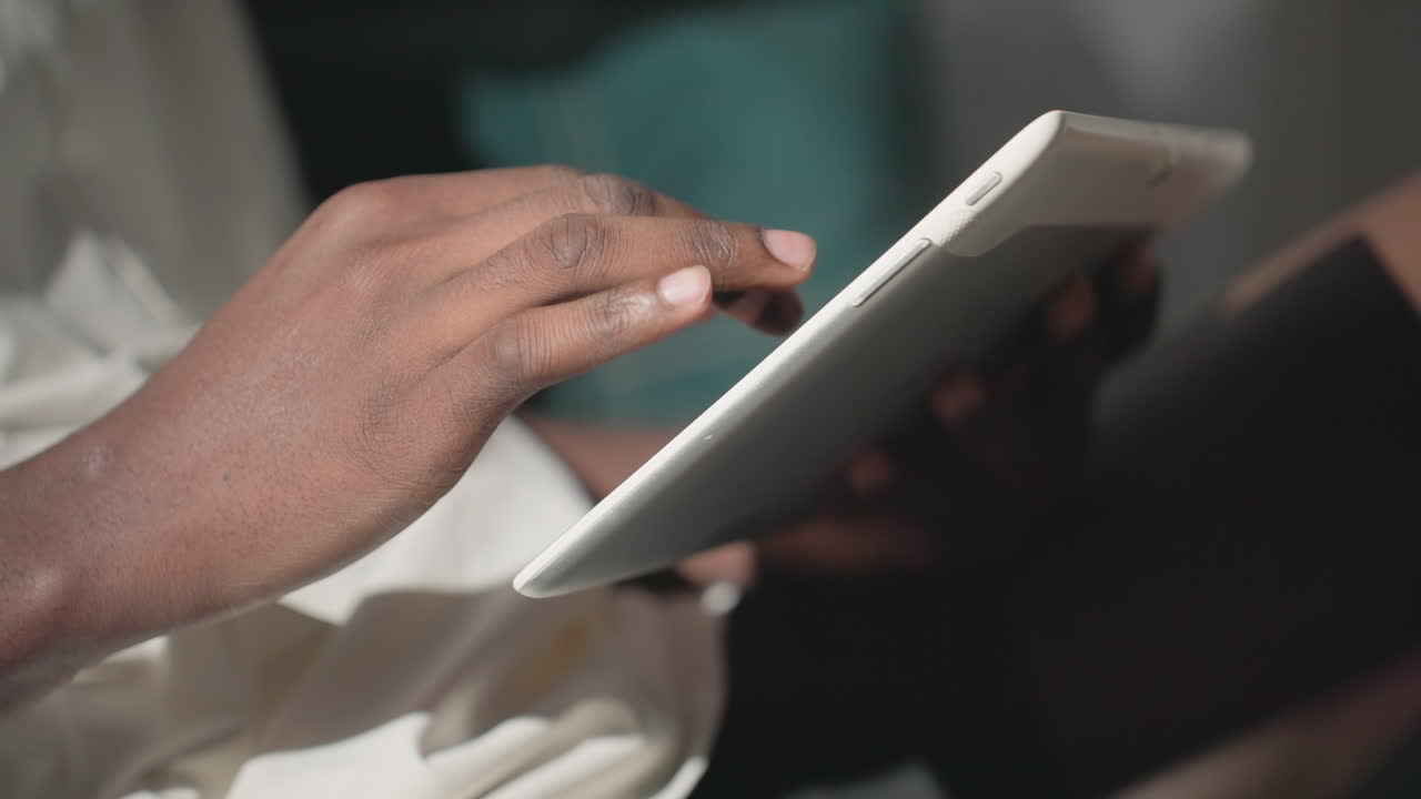 Black youth engaged in focused interaction with tablet, tapping screen, looking at device with concentration in a calm, well-lit environment. Comfortable, peaceful atmosphere for modern technology usage
