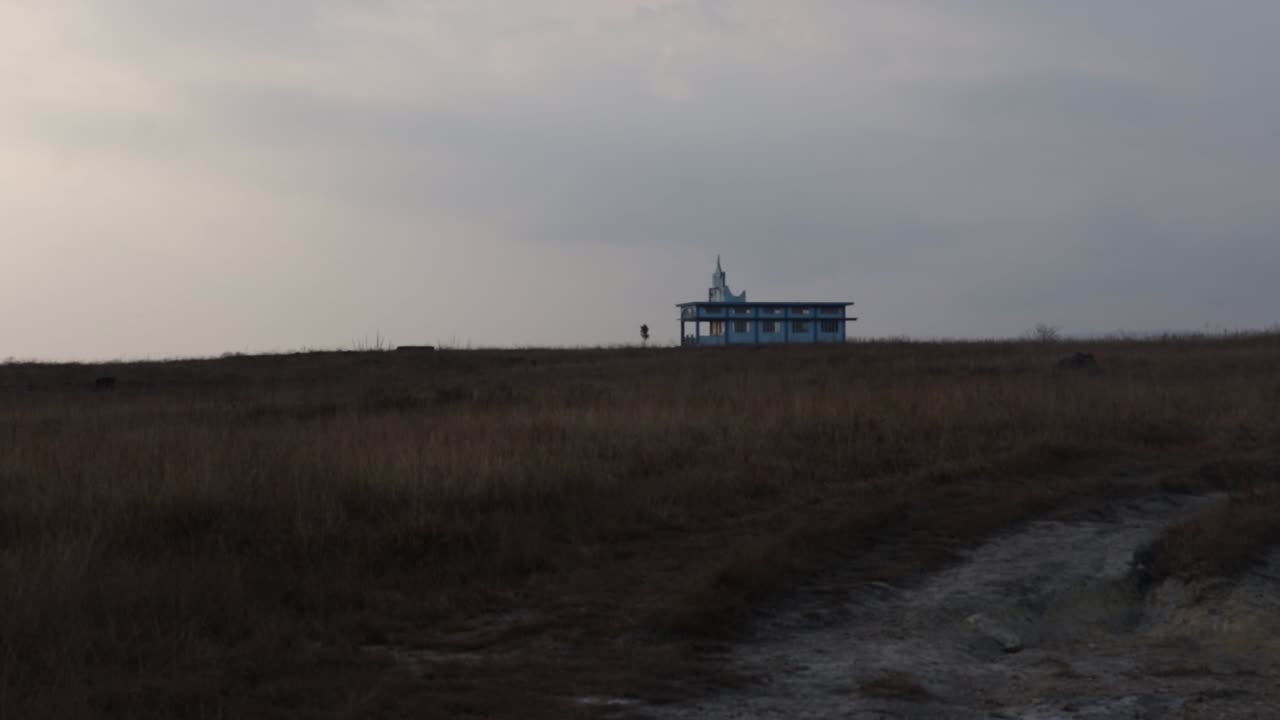 Chiesa isolata su una montagna con erba gialla e cielo piatto e nebbioso al mattino, da diverse angolazioni. Video girato a Cherrapunji, Meghalaya, India.