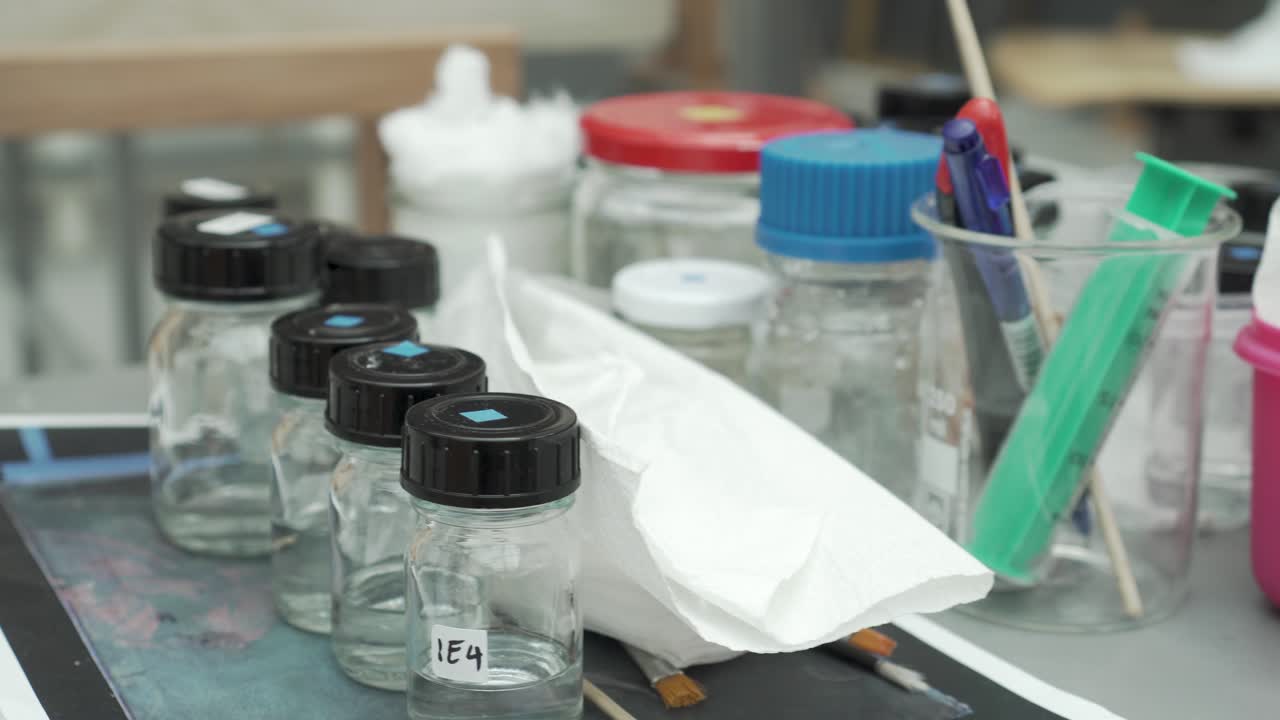 Closeup of painter - restorator workspace - laboratory glass, brushes and other tools