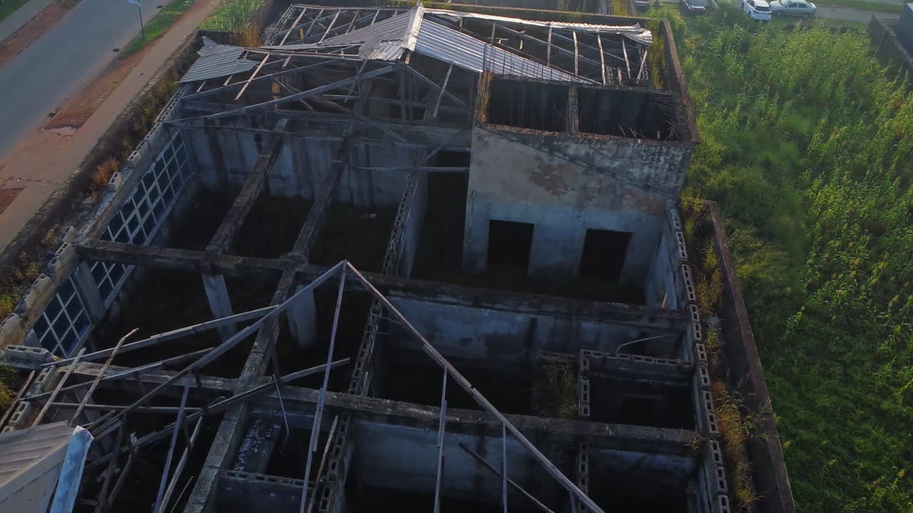 Aerial view of a devastated building with a missing rooftop. The layout and walls on the top floor of the structure can be seen