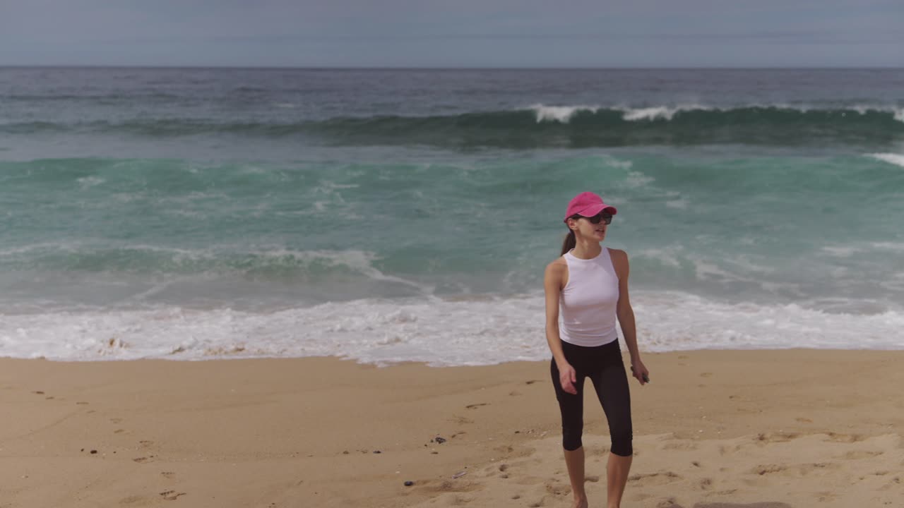 Woman walking on a sandy beach with ocean waves