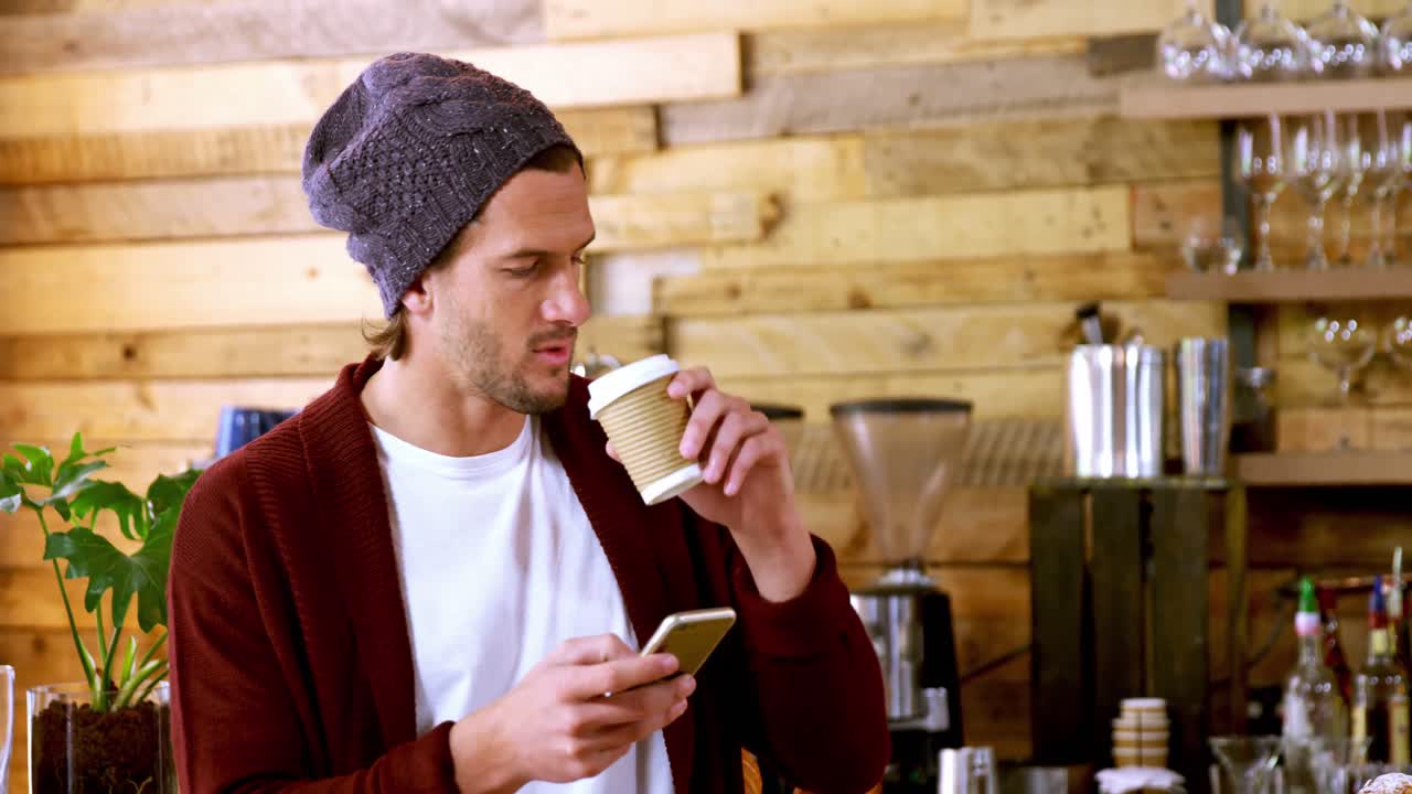 hombre usando teléfono móvil mientras toma una taza de café
