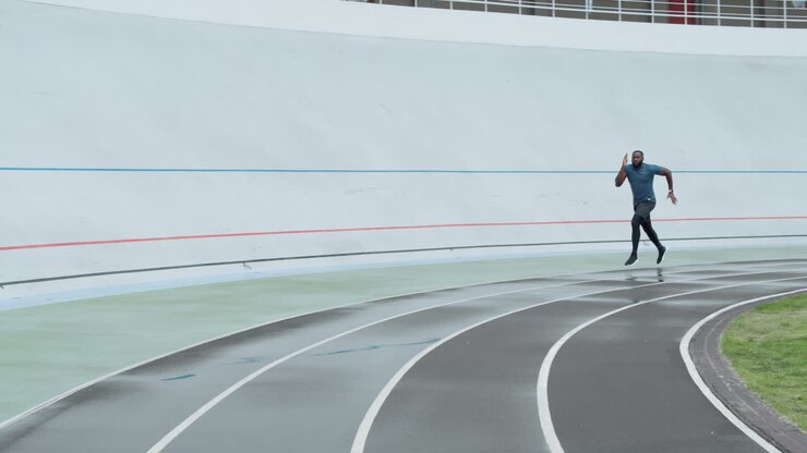 Uomo in abbigliamento sportivo che fa jogging su pista di atletica.