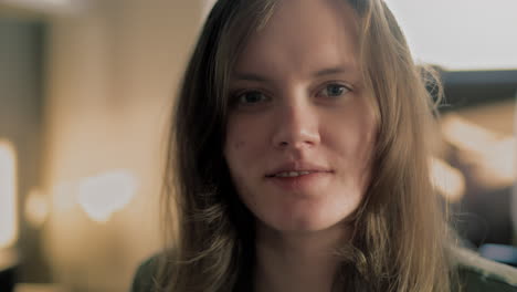 Young-white-woman-blowing-a-kiss-and-smiling-in-her-apartment-during-a-sunrise-golden-hour-in-slow-motion