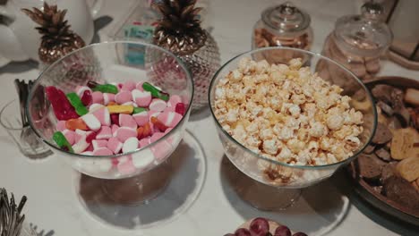 glass bowls filled with popcorn and assorted candy on elegant wedding dessert table
