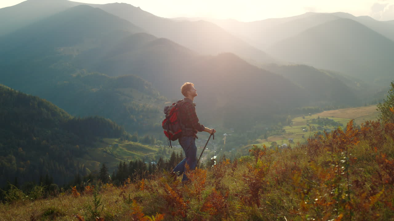 hombre activo caminando por el paisaje de las montañas. turista deportivo haciendo senderismo usando palos de trekking.
