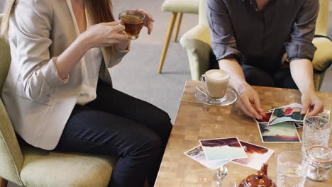 Mujeres-De-Negocios-Creativas-Reunidas-En-Un-Café-Mirando-Fotografías.