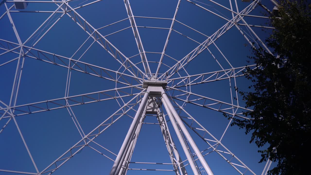 в парке большое колесо обозрения медленно вращается.