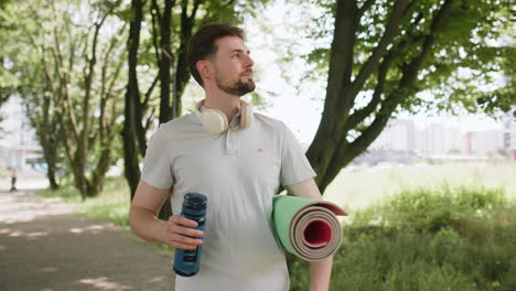 Sportlicher-Fitness-Sportläufer-Mit-Yogamatte,-Der-Nach-Dem-Training-Wasser-Aus-Der-Flasche-Trinkt