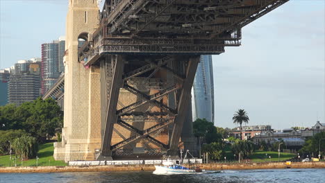 a fishing trawler boat passes underneath the sydney harbour bridge