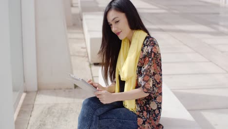 Young-woman-sitting-reading-her-tablet