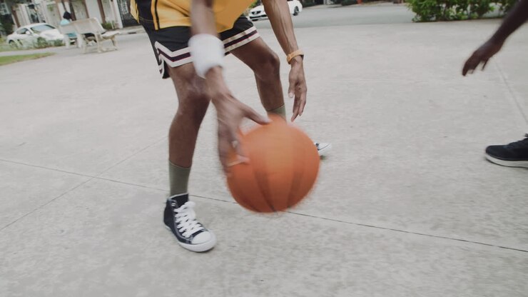 Jogadores de basquete de rua quicando a bola no chão e arremessando na cesta