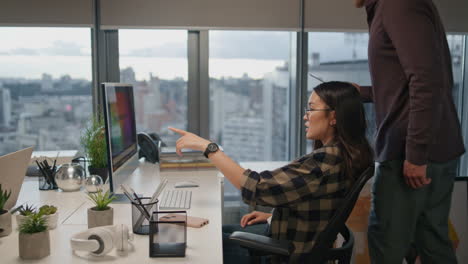 Mujer-De-Anteojos-Saludando-A-Su-Colega-En-El-Primer-Plano-De-La-Oficina.-Hombre-Mirando-Computadora