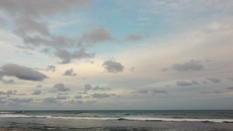 Stable-shot-of-Ocean-background,-bright-blue-sky-with-white-clouds-and-waves-at-open-sea-approaching-horizon