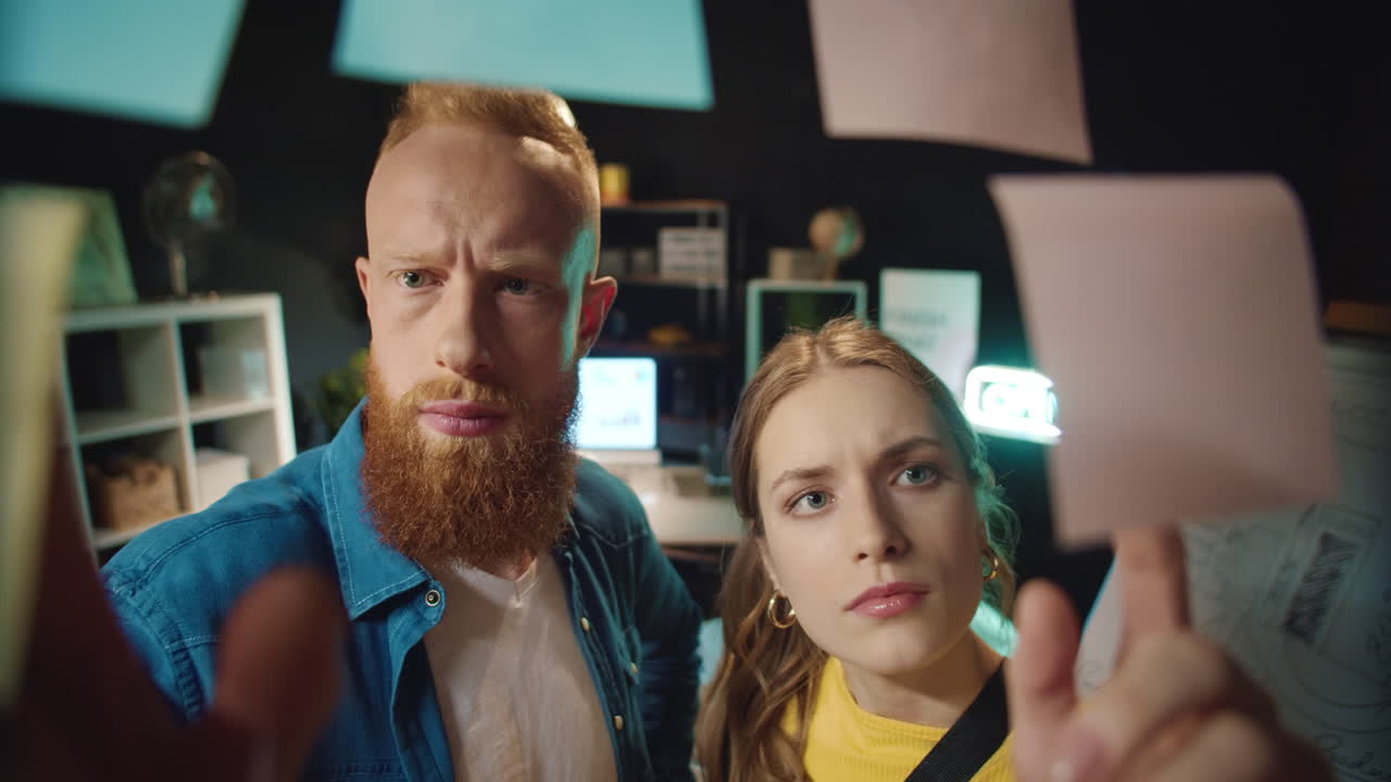 una pareja de negocios enfocada tomando pegatinas con soluciones en la oficina oscura.