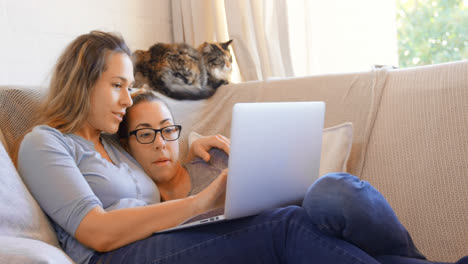 una pareja de lesbianas usando una computadora portátil en la sala de estar 4k