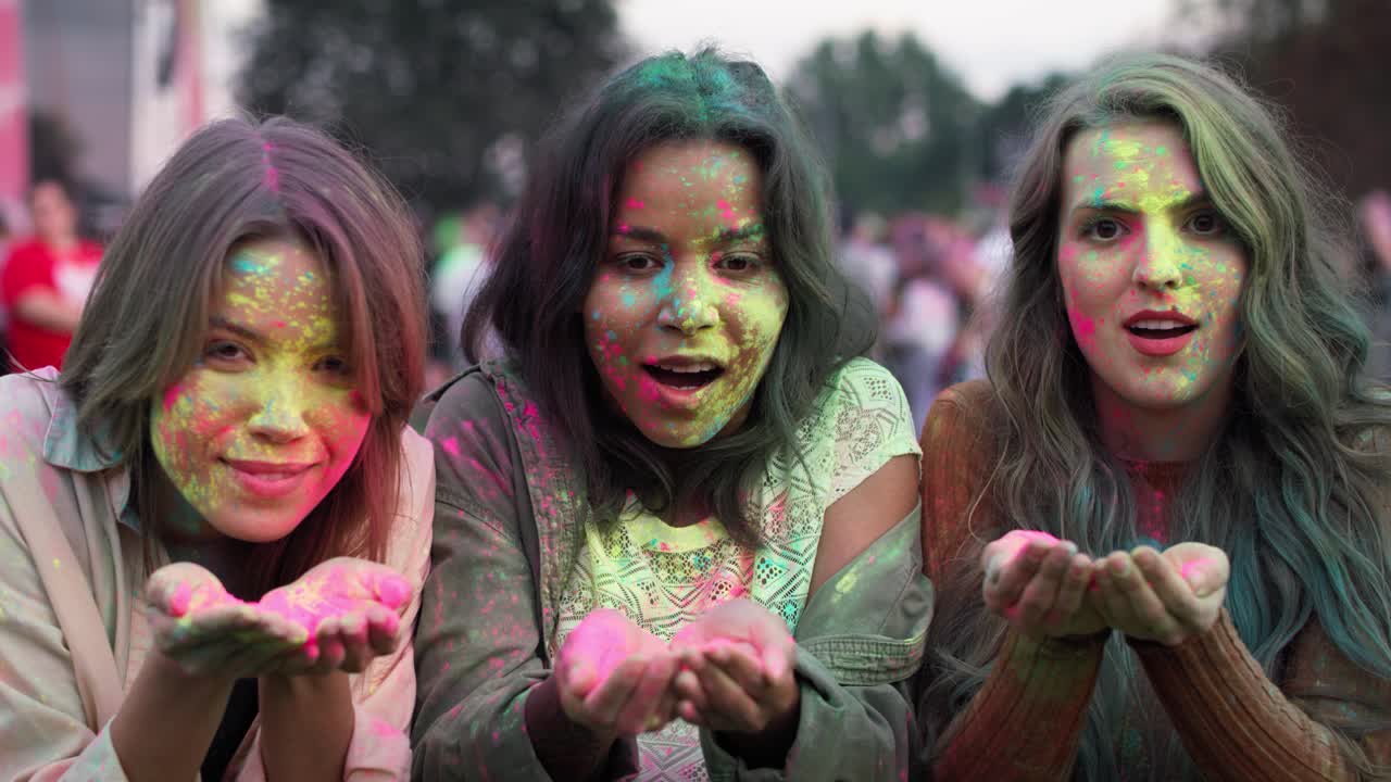 Gruppo di donne che soffiano polvere colorata al festival musicale.