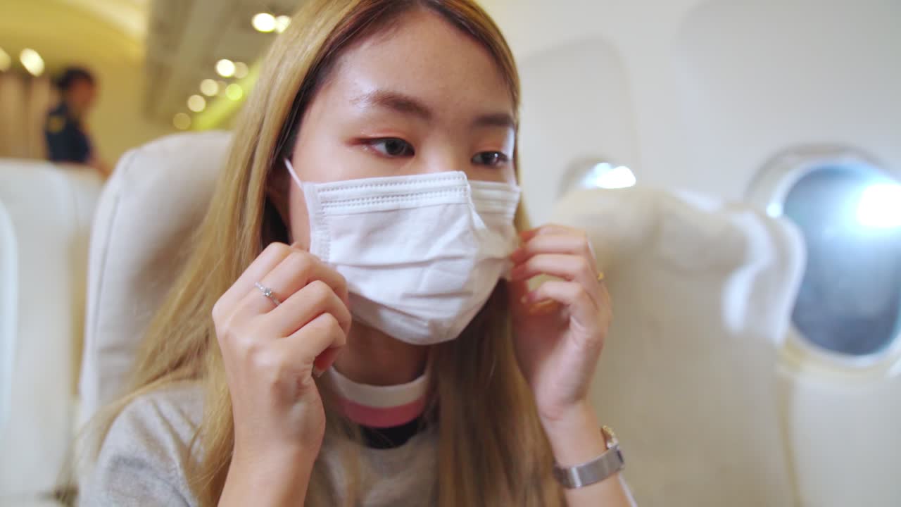 상업용 항공기에서 여행하는 동안 얼굴 마스크를 착용하는 여행자 .