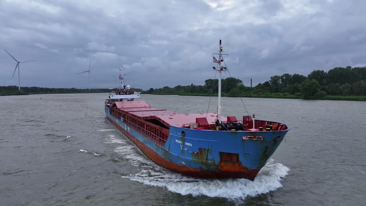 Close aerial pan of cargo ship Wilson Odra on river in cloudy Netherlands