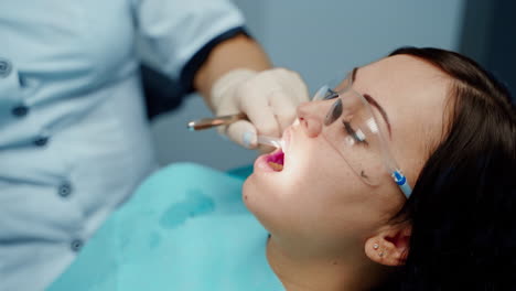 dentist working with patient. female dentist in uniform and gloves using dental instruments