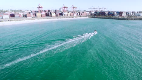 una toma aérea de un niño adolescente skurfing detrás de un barco de velocidad en el puerto de fremantle