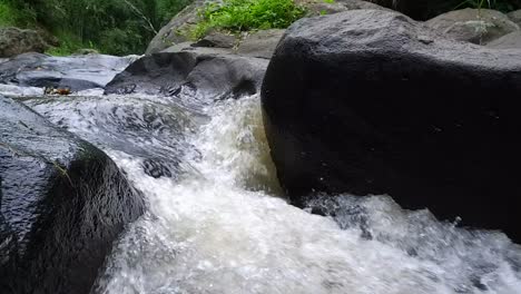 the rushing river water flow through the black rocks