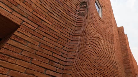 camera tilts up along a tall brick structure