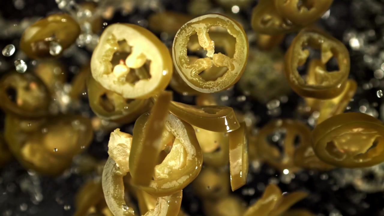 Fette di peperoncino jalapeño verde che cadono al super rallentatore