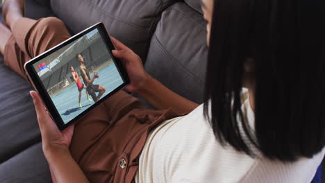 compuesto de una mujer en el sofá en casa viendo atletismo corriendo evento en la tableta