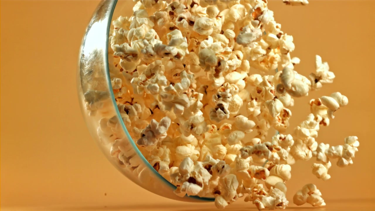Popcorn Spilling from a Glass Bowl in Slow Motion