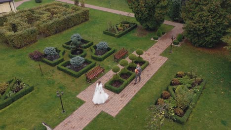 Schöne-Braut-Und-Bräutigam-Mit-Blumenstrauß-Im-Park,-Die-Sich-Küssen,-Brautpaar,-Luftaufnahme