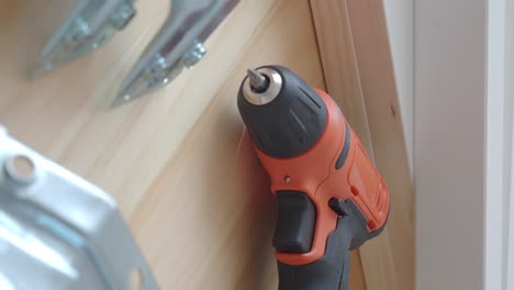 orange electric drill on wooden surface with other tools