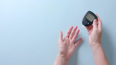 hands of caucasian woman checking blood sugar level using glucometer, copy space, slow motion