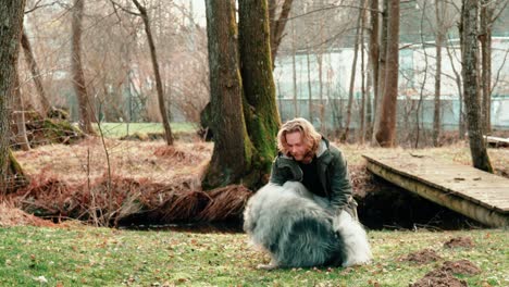 this young blond man tries to show his dog a new trick, but the dog doesn't seem to be too enthusiastic about it and probably prefers to be petted a little