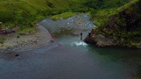 drone shot of people jumping and swimming in a river