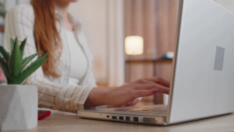 Junge-Frau-Mit-Laptop,-Sitzt-Am-Tisch-Und-Arbeitet,-Tippt-Im-Homeoffice-Auf-Der-Tastatur