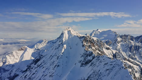 aerial drone view of the italian alps in wintertime.
flying over the snowy mountains during sunny day with clear blue sky.