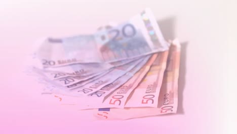 animation of close up of euro bills flying against pink gradient background